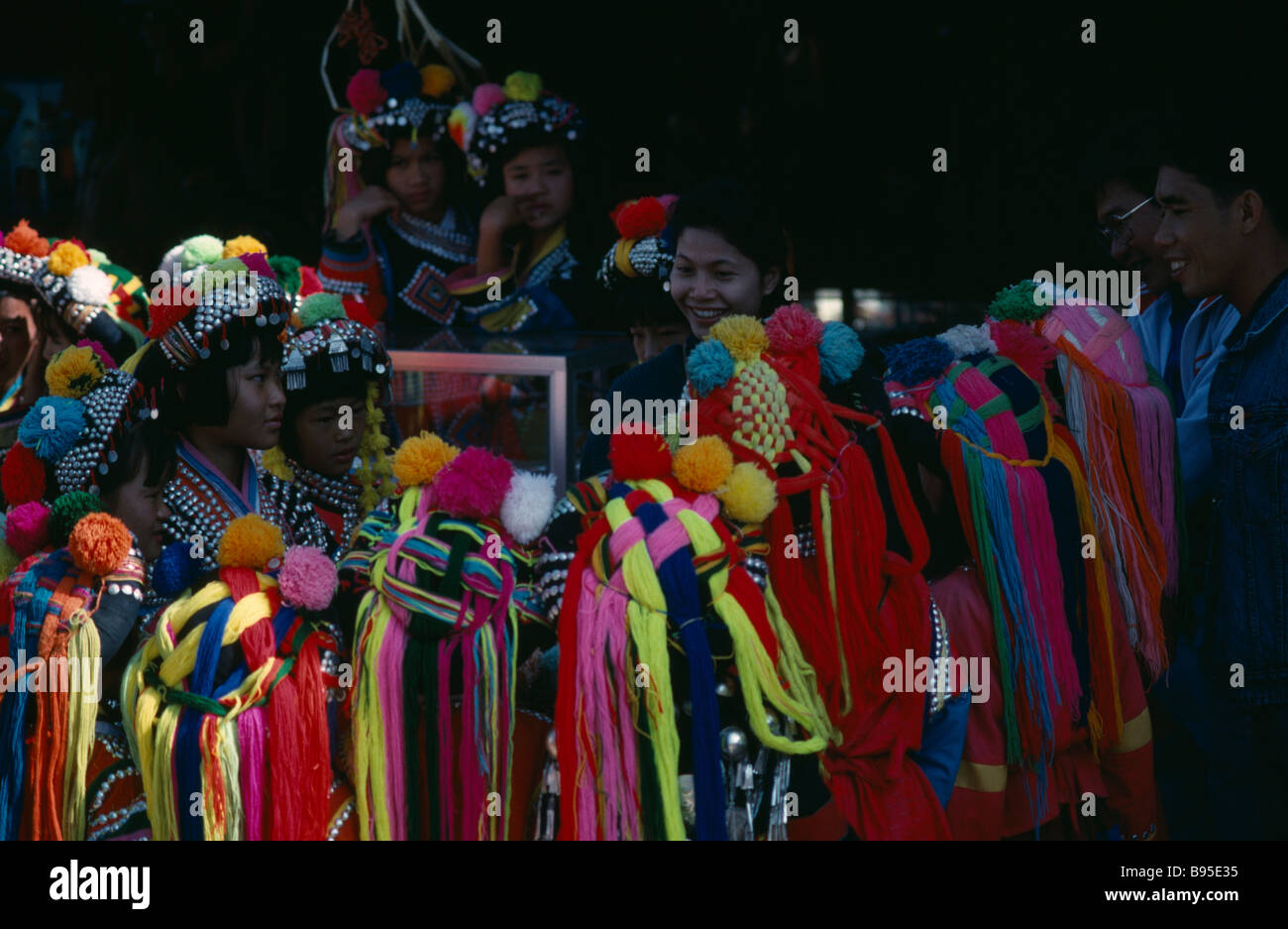 THAILAND Menschen Akha Mädchen tragen hell farbigen Kopf-Kleider um Touristen versammelt. Stockfoto