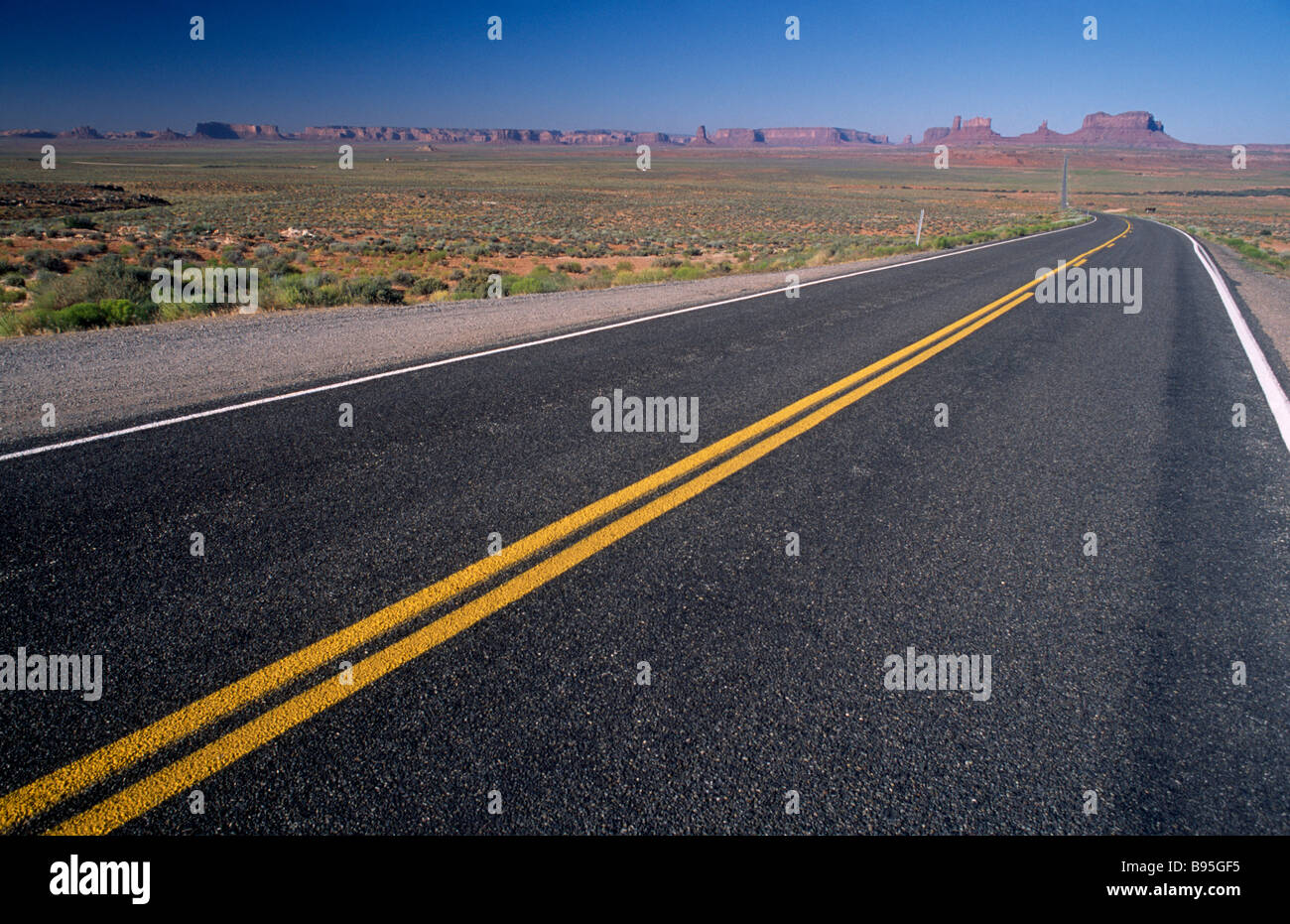 USA, Arizona, Monument Valley, U.S. Highway 163. Blick über leere Strecke von der Straße in Richtung Tal mit entfernten Felsformationen. Stockfoto