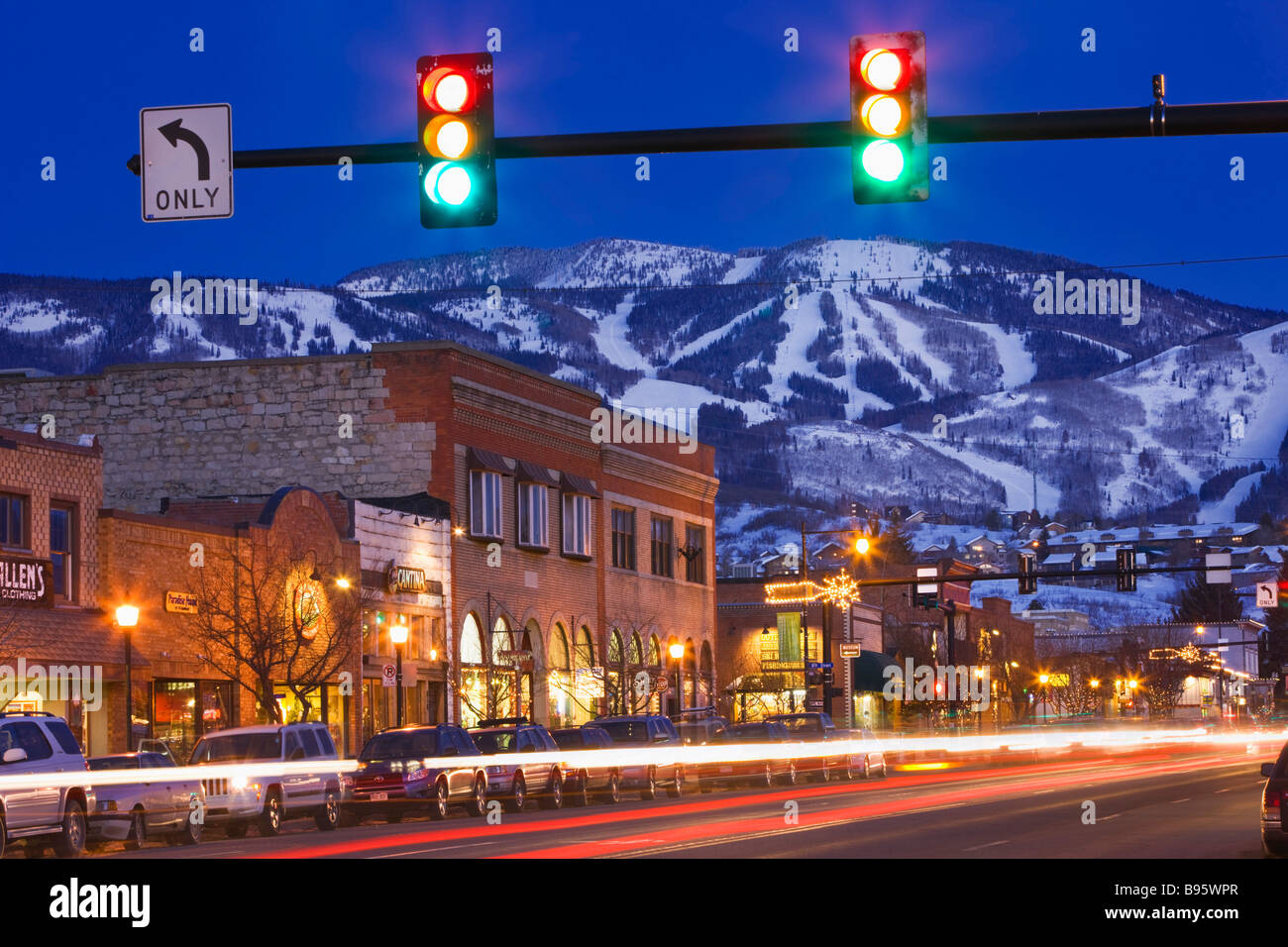 USA Colorado Steamboat Springs beschäftigt Straßenszene in Abend mit Ampel an der Straßenkreuzung und Snow capped Hügel im Hintergrund Stockfoto