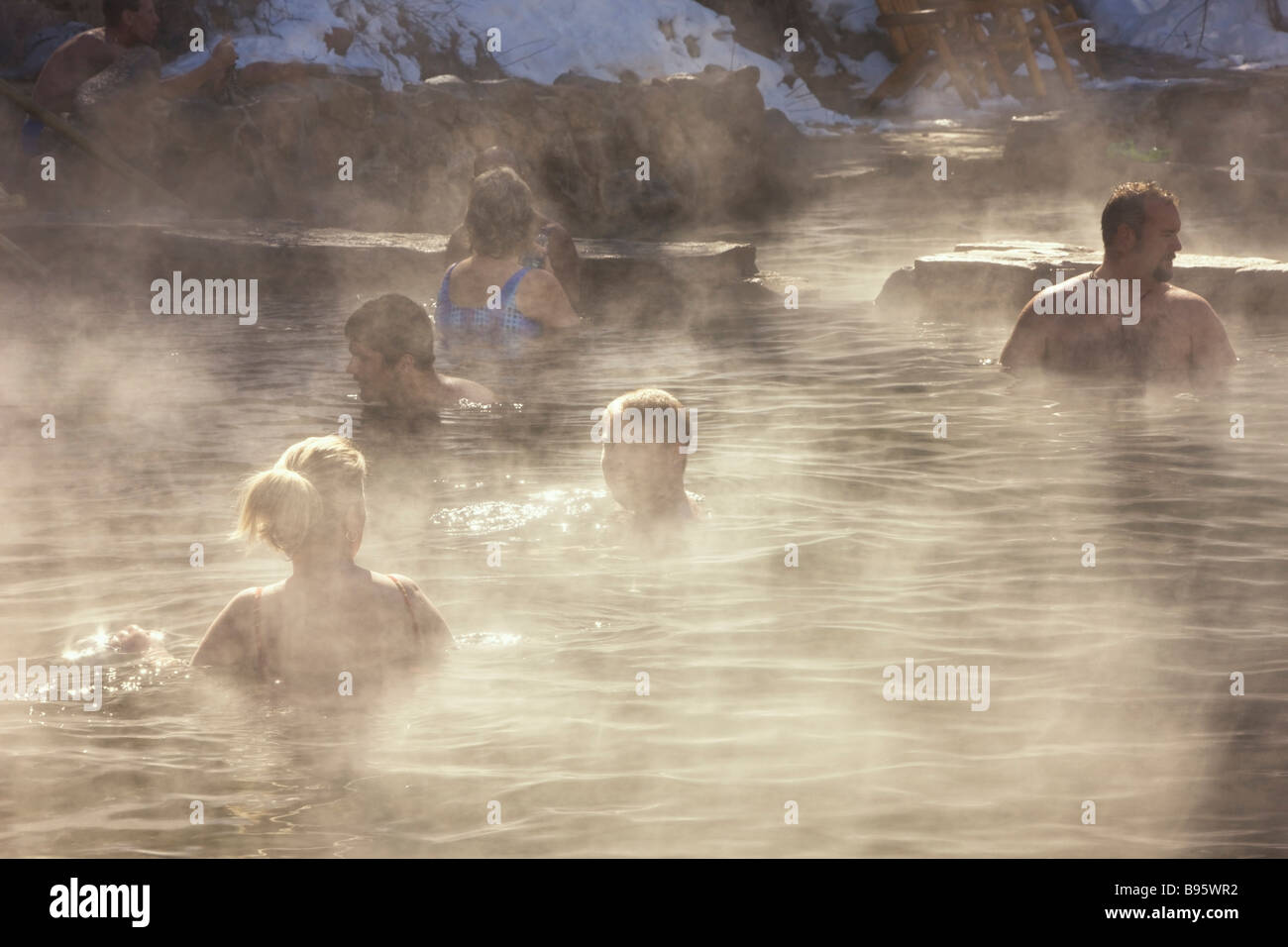 USA Colorado Steamboat Springs Leute sitzen im warmen Außenpool des Spa resort mit Dampf steigt in der kalten Luft. Stockfoto