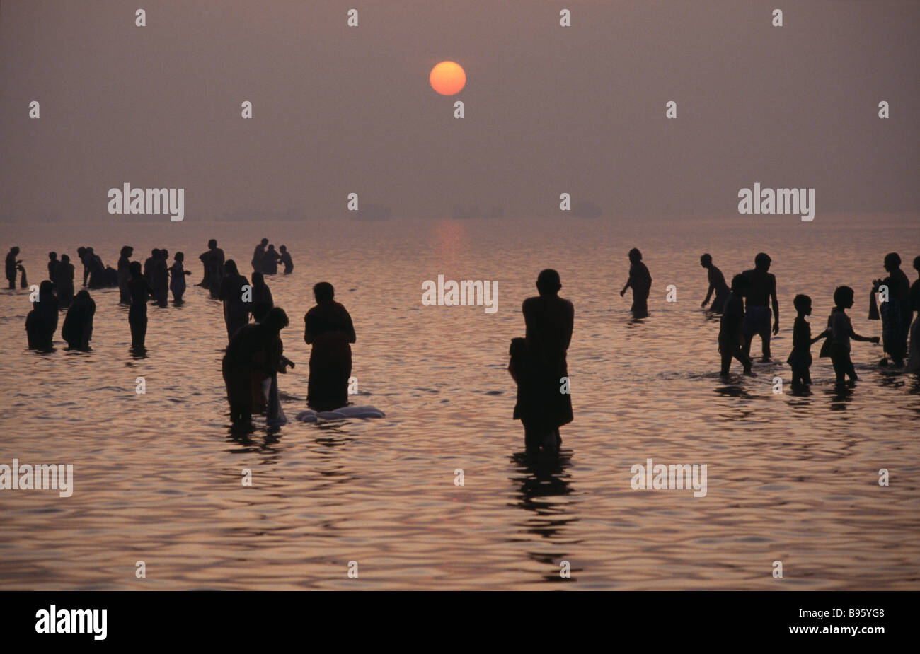 Indien in Südasien Uttar Pradesh Allahabad Magh Mela Festival Fluss Ganges Pilger Baden im flachen Wasser bei Sonnenuntergang. Stockfoto
