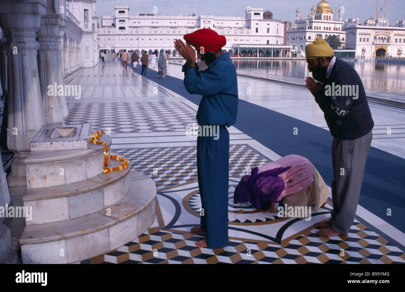 Indien Punjab Amritsar Sikh Golden Tempel Pilger beten am Schrein mit Girlande aus Ringelblumen über Marmorstufen gelegt Stockfoto
