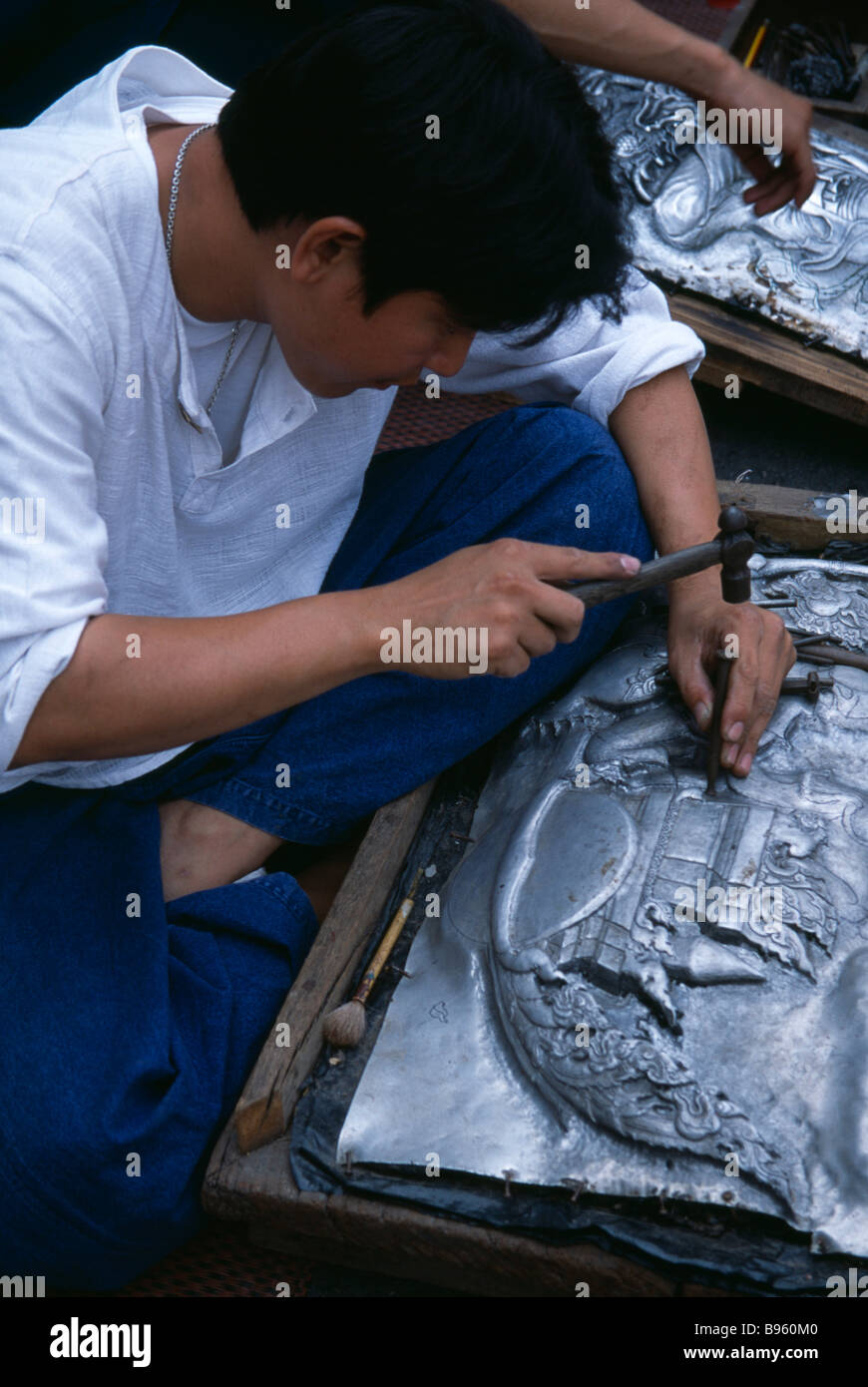 THAILAND Nord Chiang Mai Tha Phae Road junge Mann arbeitet auf Metallarbeiten Relief Bild mit Hammer und Durchschlag Stockfoto