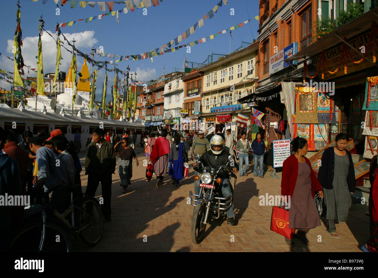 Ein Mann auf einem Motorrad und Menschen finden ihren Weg rund um Boudhanath Stupa in Kathmandu, Nepal. Stockfoto