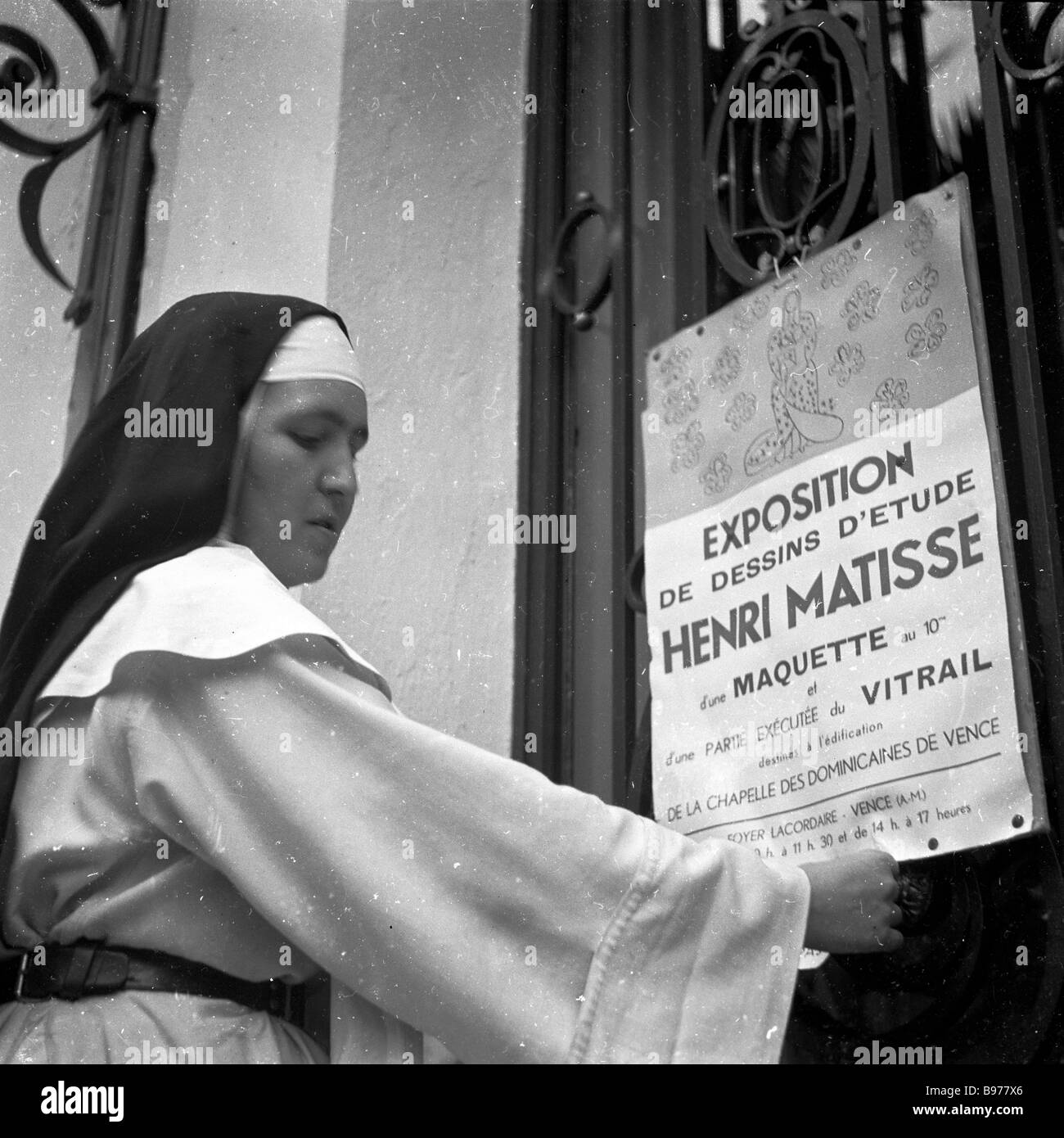1951, historische, eine katholische Nonne stellt ein Poster über eine Ausstellung des französischen Künstlers Henri Matisse Designs für die Chapelle du Rosaire in Vence. Stockfoto