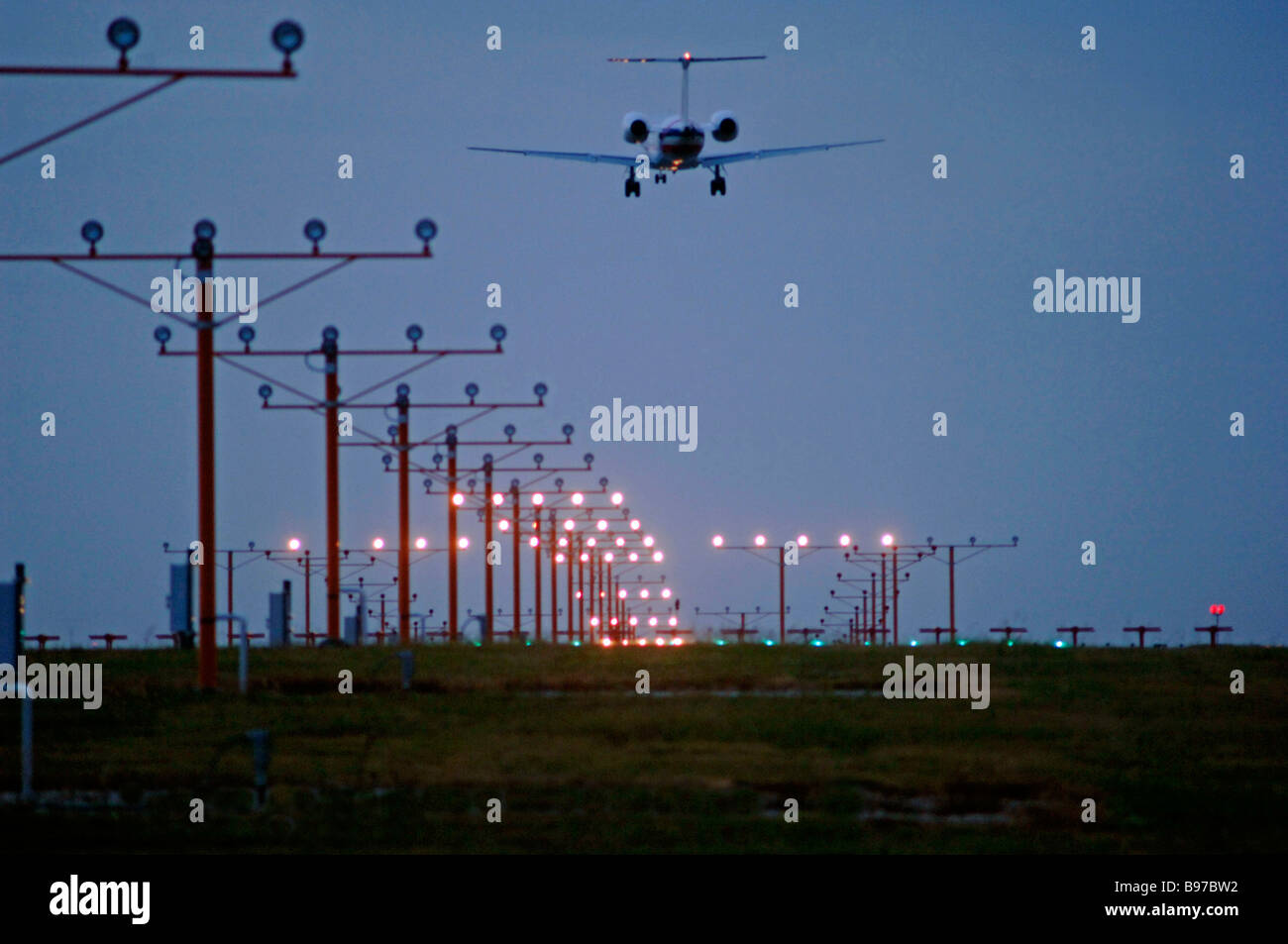 Düsenverkehrsflugzeug auf Ansatz über Start-und Landebahn Lichter am DFW International Airport unter bewölktem Himmel aber klarem Wetterbedingungen Stockfoto