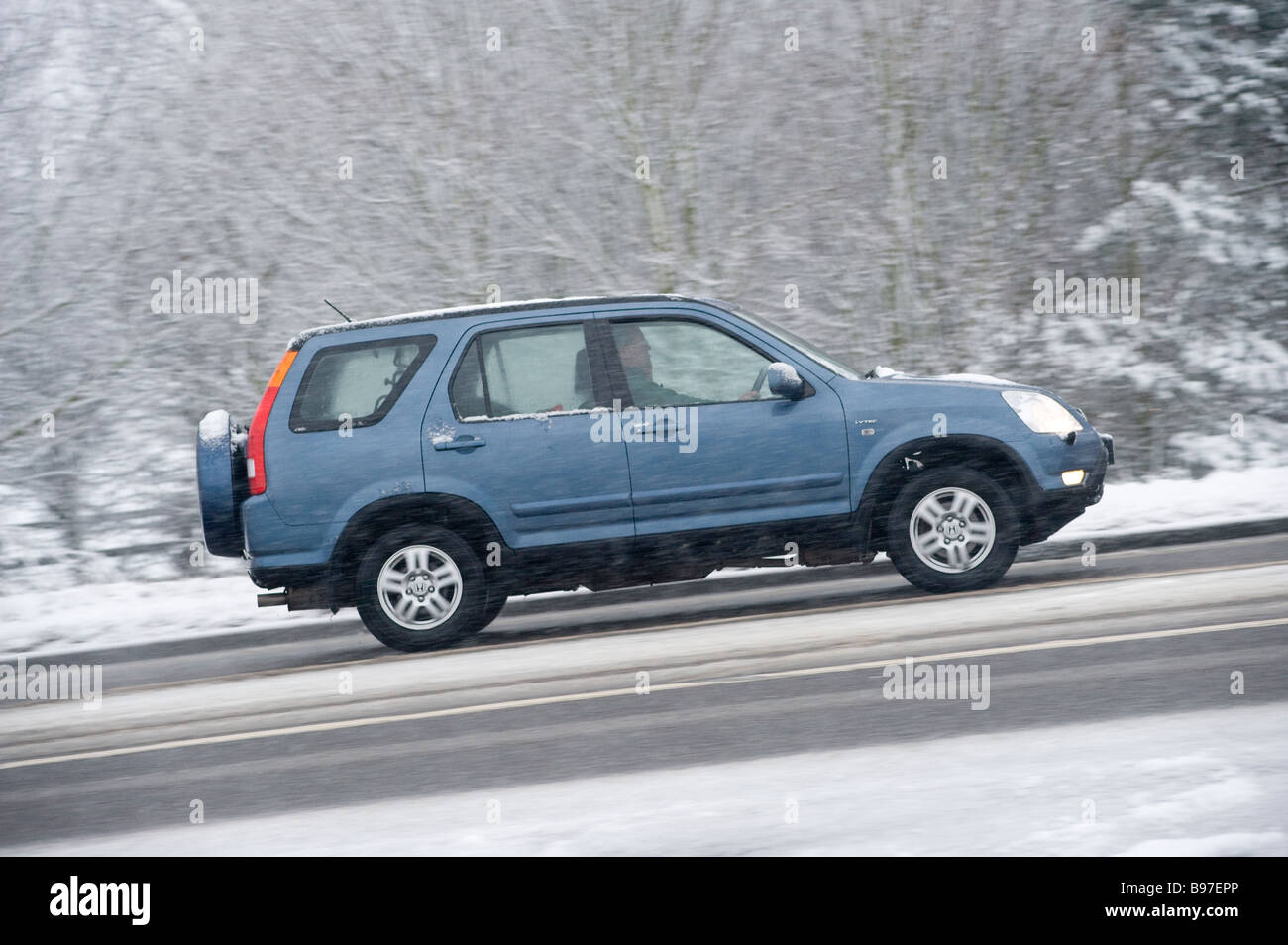 Seitenansicht eines blauen Honda Hrv 4 x 4 Autos fahren entlang einer Schnees bedeckt Straße an einem Wintertag in england Stockfoto