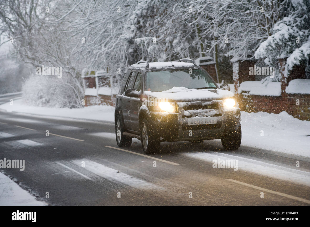 Einsamer 4 x 4 Geländewagen fahren auf Schnee bedeckt Straße im grünen an einem Wintertag in england Stockfoto