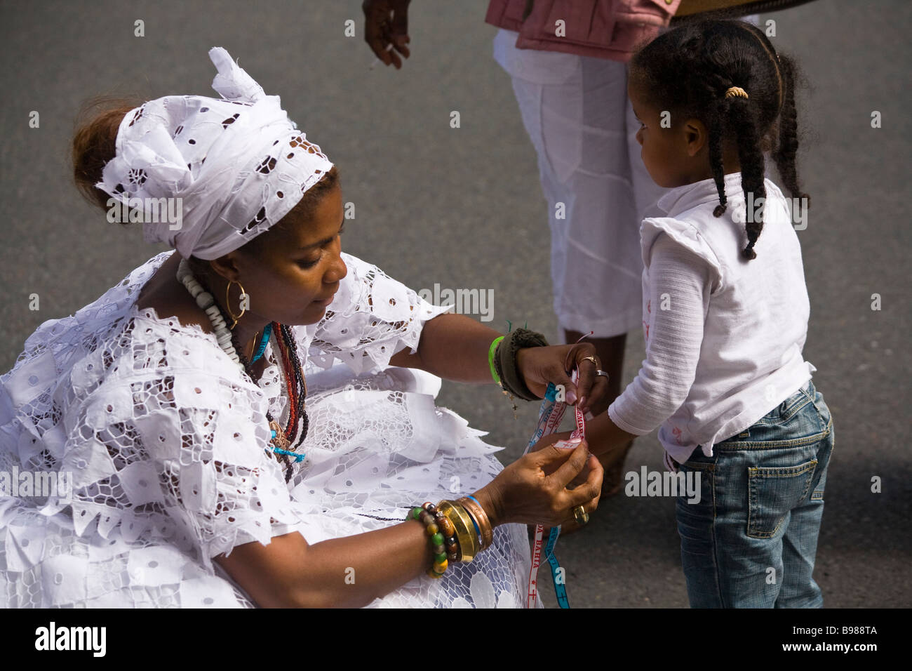 Eine traditionelle bahianische Frau ein Kind eine Senhor Do Bonfim Glück Band anzubieten. Stockfoto