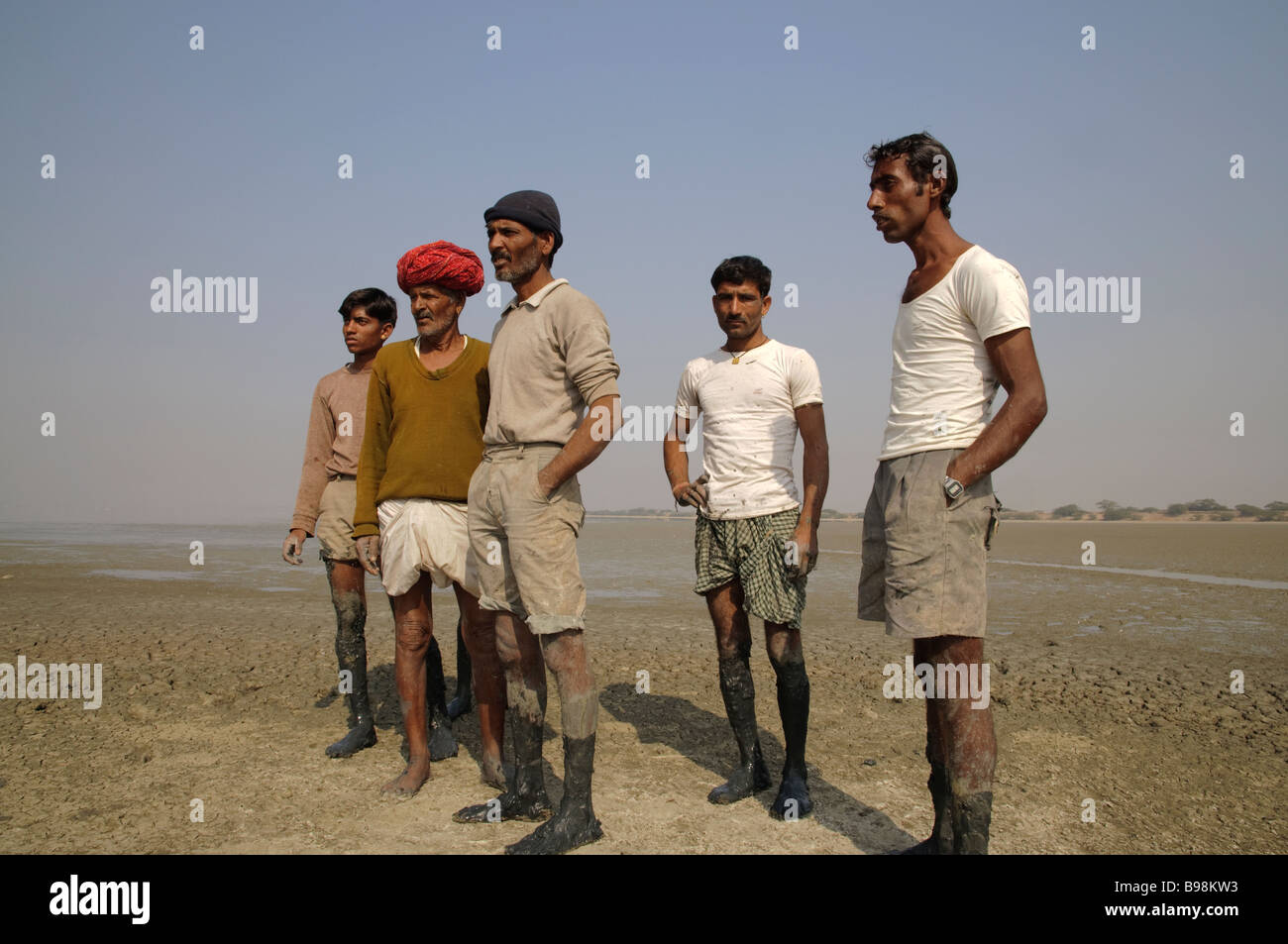 Eine Gruppe von indischen Arbeitern mit schlammigen Füßen sind einige unsichtbare Aktion in der Aue Sambhar See Rajasthan Indien betrachten Stockfoto