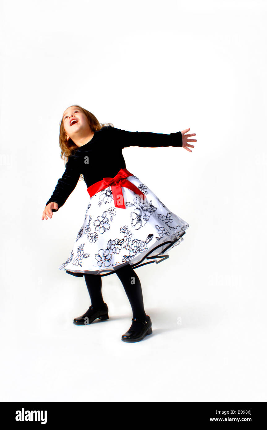 Junges Mädchen drehen, quirlen und spielen in einem gerüschten Kleid auf weißem Hintergrund Stockfoto