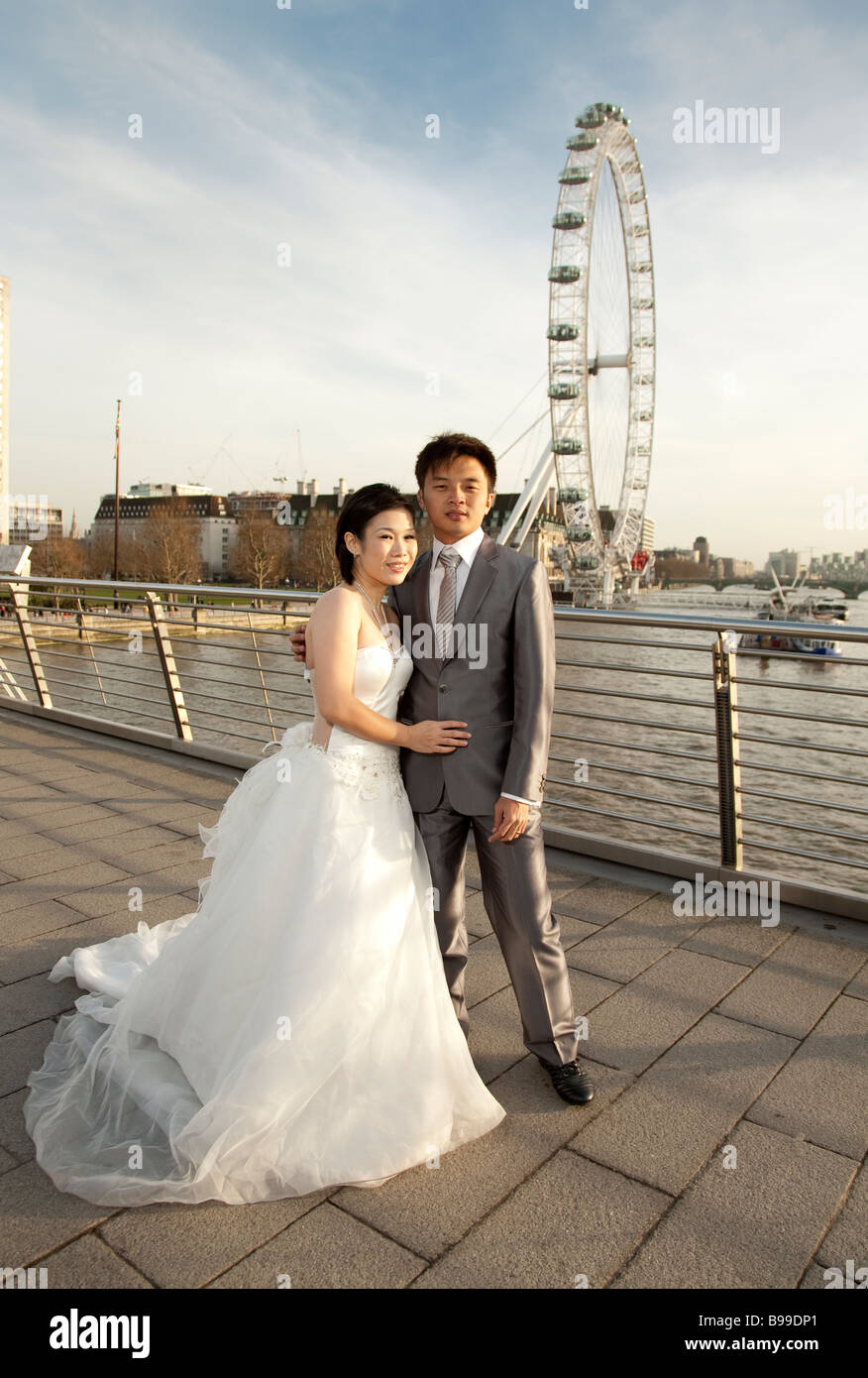 eine orientalische Braut und Bräutigam in Brautkleid und Anzug posieren vor London Eye Stockfoto
