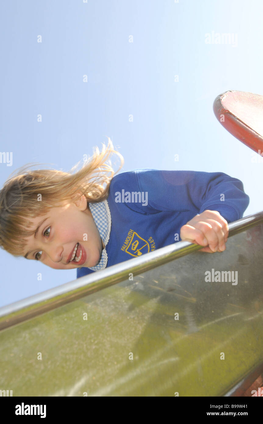 Ein sechs Jahre altes Mädchen in Schuluniform auf einer Rutschbahn Stockfoto