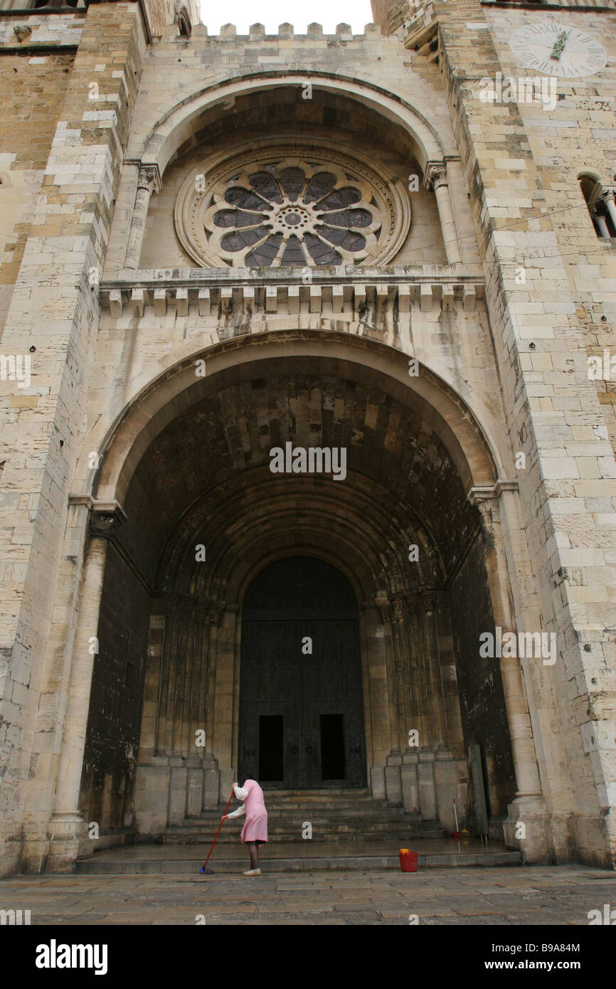 Eine Frau fegt die Schritte von der Kathedrale von Lissabon oder Santa Maria Maior de Lisboa aber allgemein bekannt als das Sé de Lisboa, Portugal Stockfoto