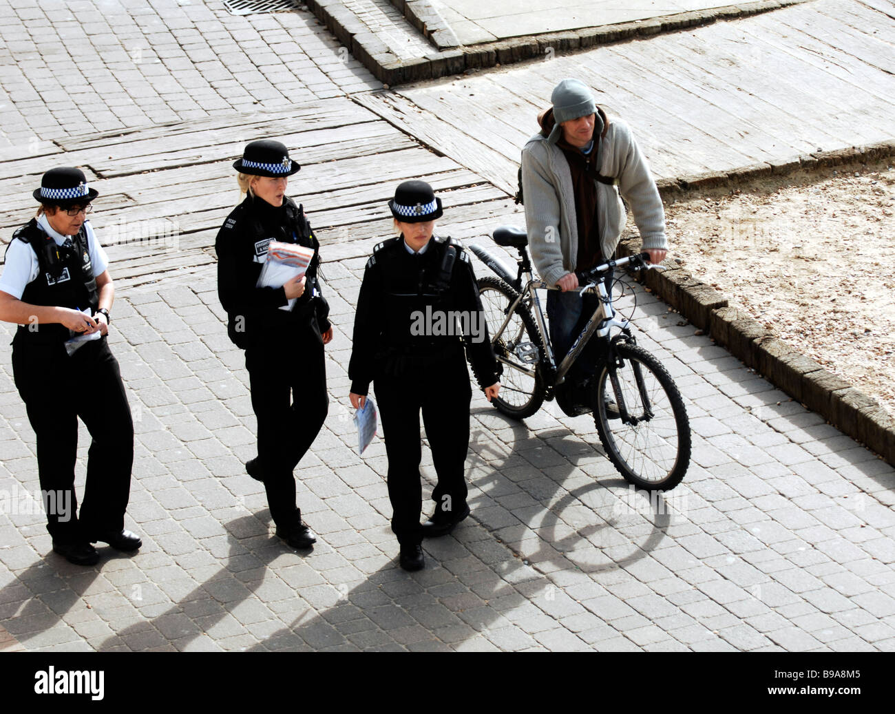 Ein Radfahrer passiert drei PCSO s der Polizei-Community an der Küste von Brighton in Großbritannien Stockfoto
