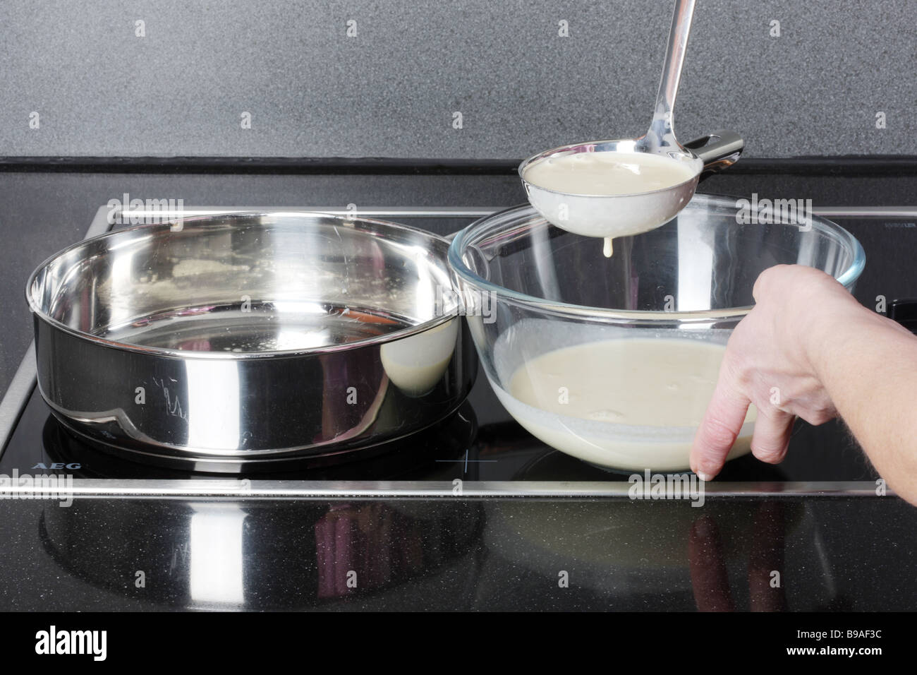 Frau Pfanne Pfannkuchen-Mischung hinzufügen Stockfoto