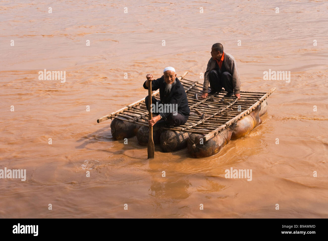 Sala ethnische Minderheit Mann muslimischen rafting auf schwimmenden Blase der Schafe Haut als schwimmenden Floß Yellow River China verwendet Stockfoto