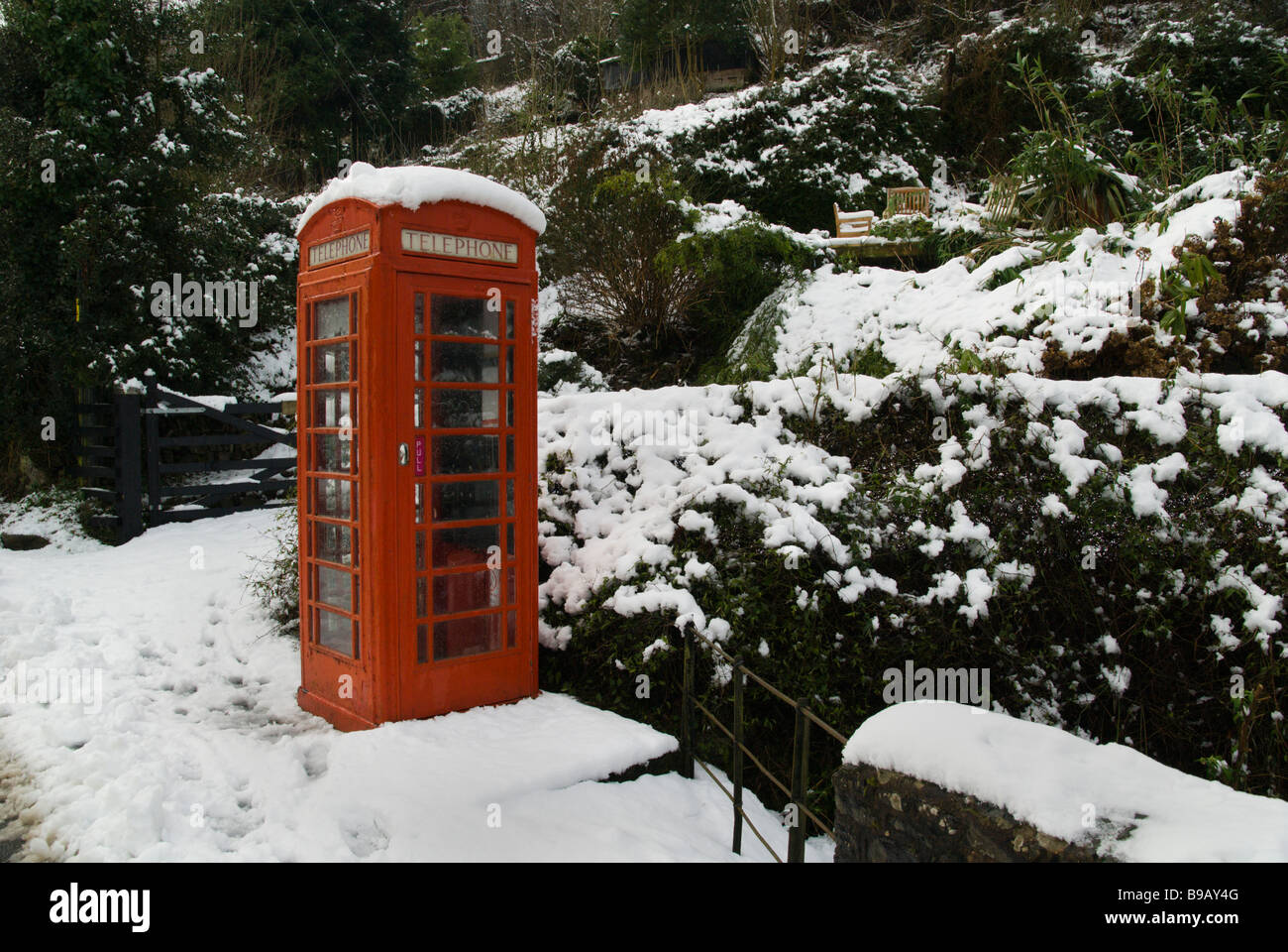 Alte rote Telefonzelle im Schnee in ländlicher Umgebung Stockfoto