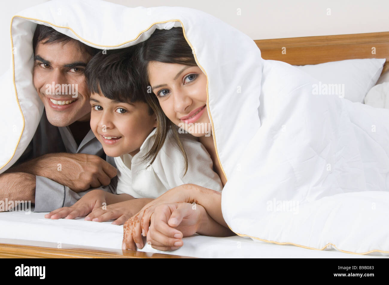 Paar liegen unter dem Deckmantel mit ihrem Sohn und lächelnd Stockfoto