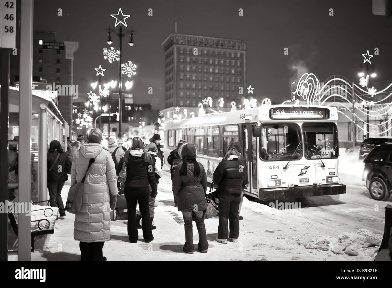 Pendler, die an einer Bushaltestelle an einem kalten Wintertag in der Innenstadt von Winnipeg, Manitoba, Kanada warten. Stockfoto