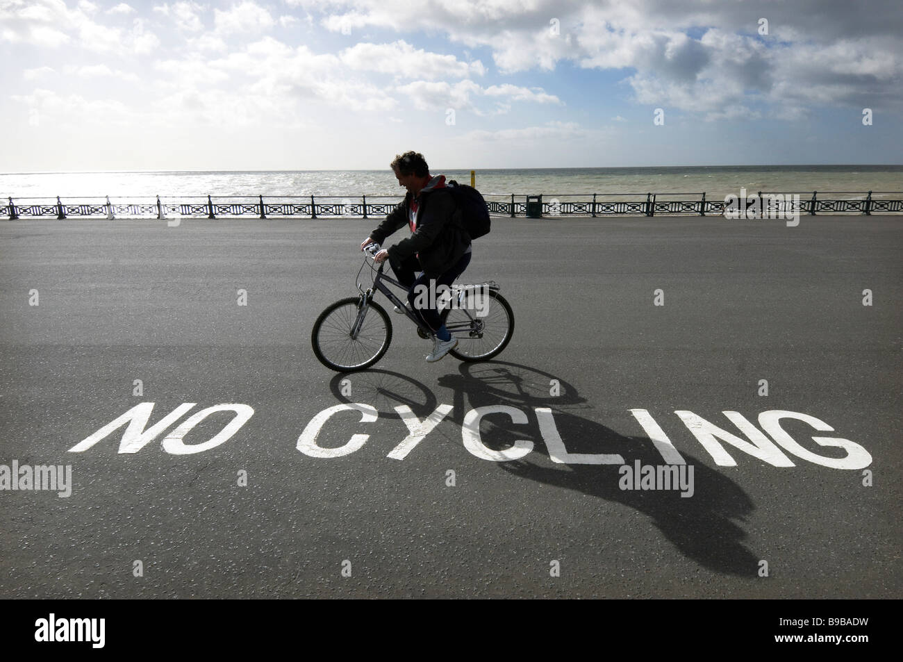 Ein Radfahrer ignorieren ein "No Radfahren Schild am Strand von Brighton und Hove. Stockfoto