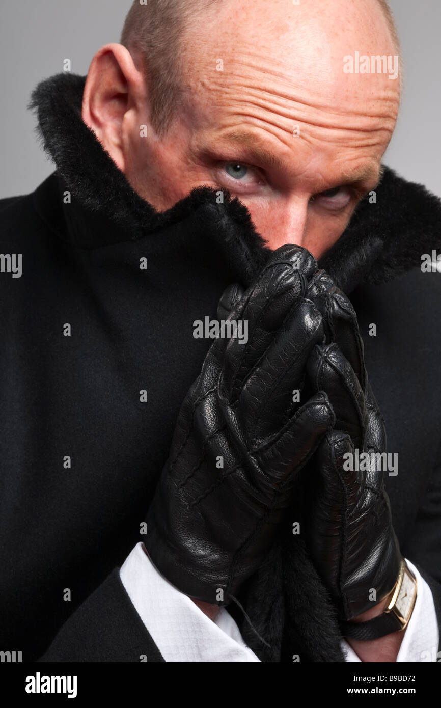 Mann im schwarzen Mantel mit Pelzkragen Deckung eines Teils seines Gesichts Stockfoto