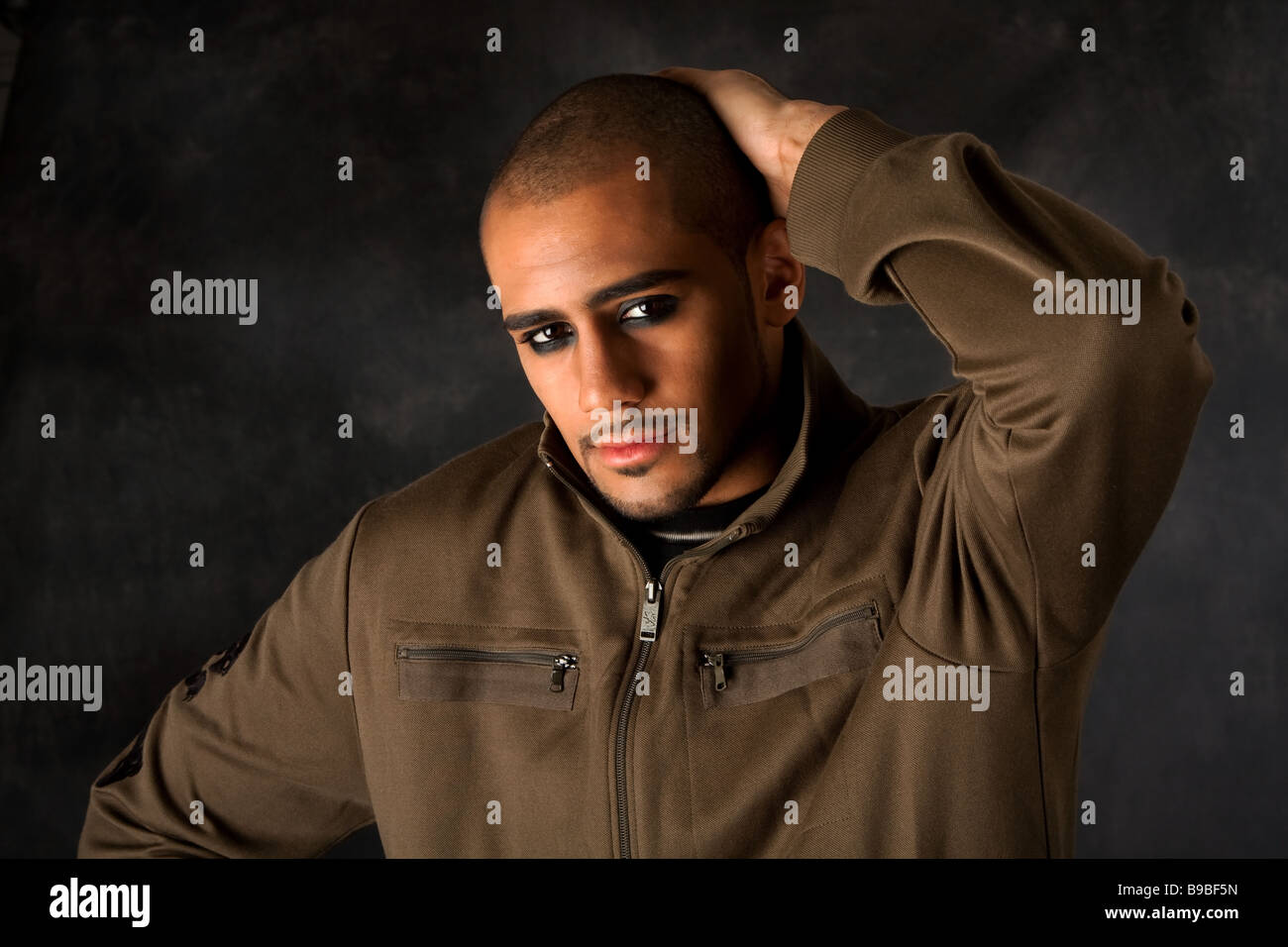 Gut aussehend afrikanischen Hispanic Mann runzelte die Stirn mit starken macho Ausdruck und dunklen Augen in grüner Weste und Hand auf Kopf Stockfoto