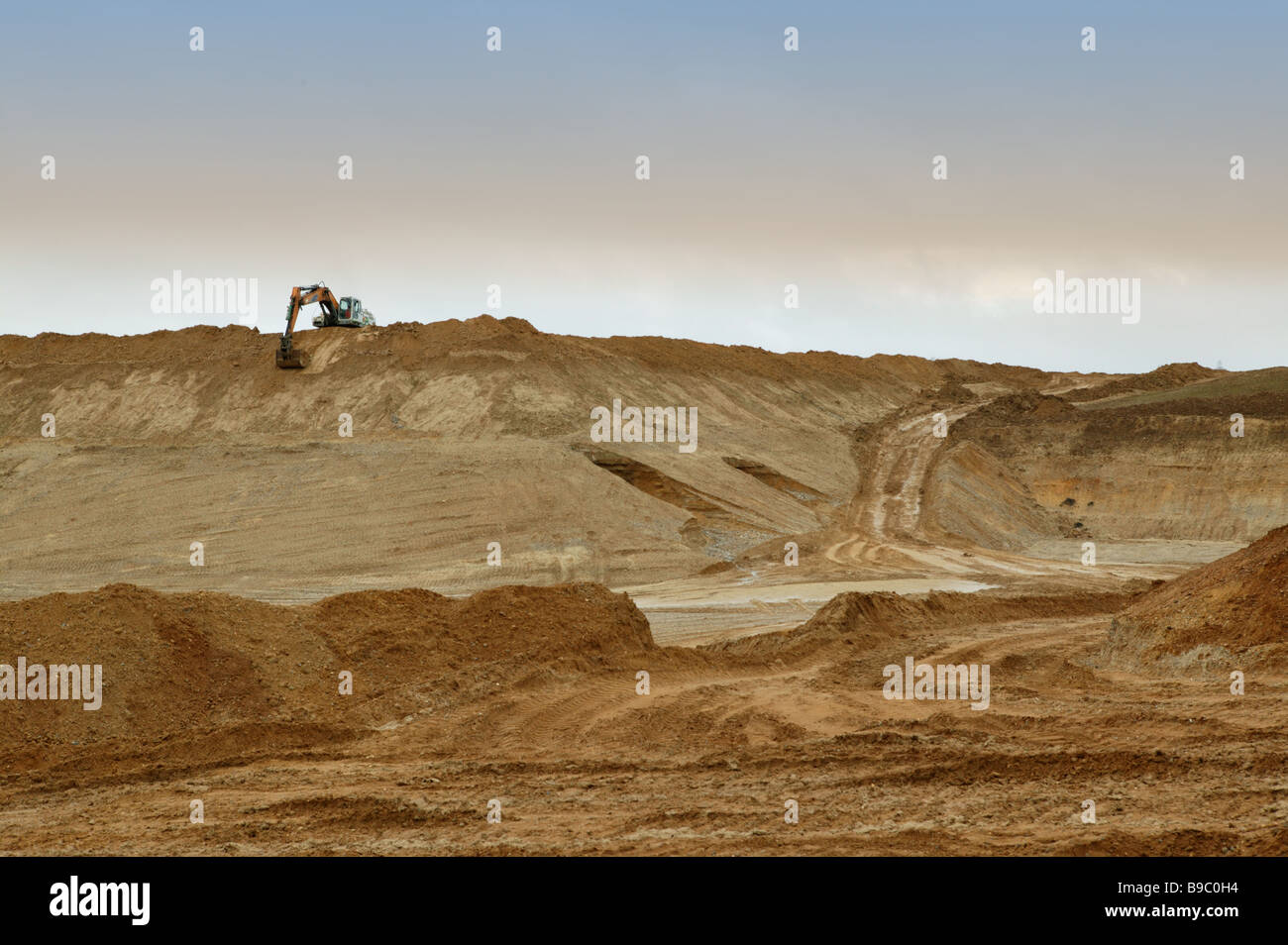 einzigen großen Bagger arbeiten in offenen Sandgewinnung Ort umgeben von großen Berge von sand Stockfoto