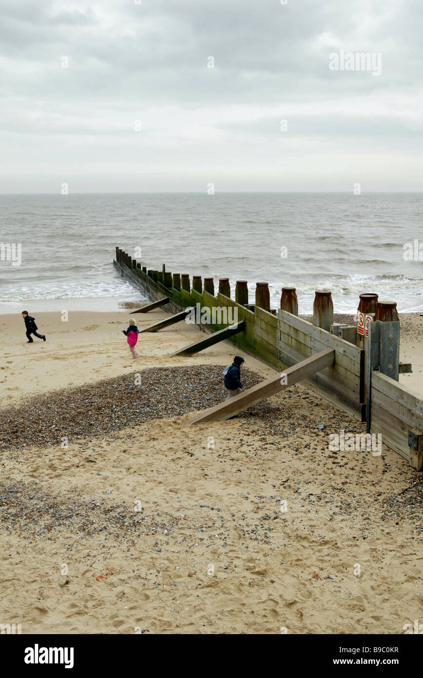 Blick auf die Ostküste von Großbritannien mit einem großen Meer Buhne ragt ins Meer mit 3 Kinder spielen am Strand im Vordergrund Stockfoto