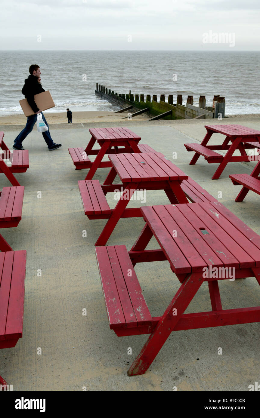 roten Sofas vor einem Meer-Café-Restaurant geben eine grafische Veranschaulichung des Sitzens auf der Strandpromenade mit Passanten und Stockfoto