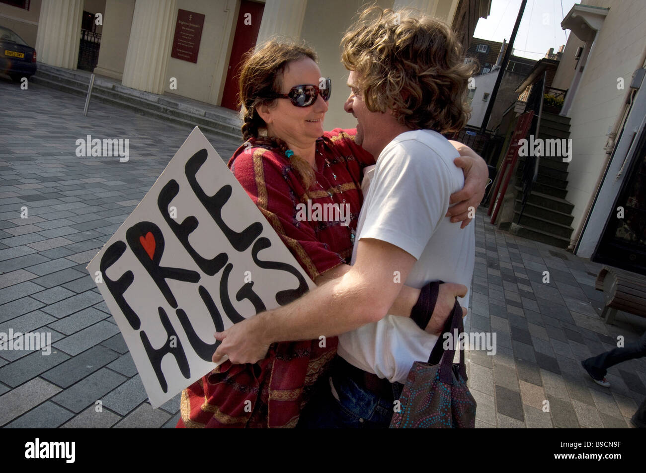 Ein junges Paar geben sich gegenseitig eine spontane Umarmung im Zentrum von Brighton während einer Veranstaltung "Free Hugs" Stockfoto