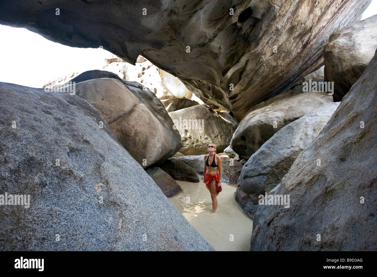 Eine Frau geht unter die riesigen Felsbrocken in die Bäder auf Virgin Gorda BVI Stockfoto