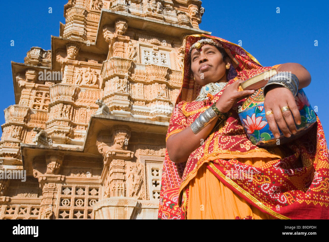 Frau mit einem Topf mit einem Turm im Hintergrund, Vijay Stambh, Chittorgarh Fort, Chittorgarh, Rajasthan, Indien Stockfoto