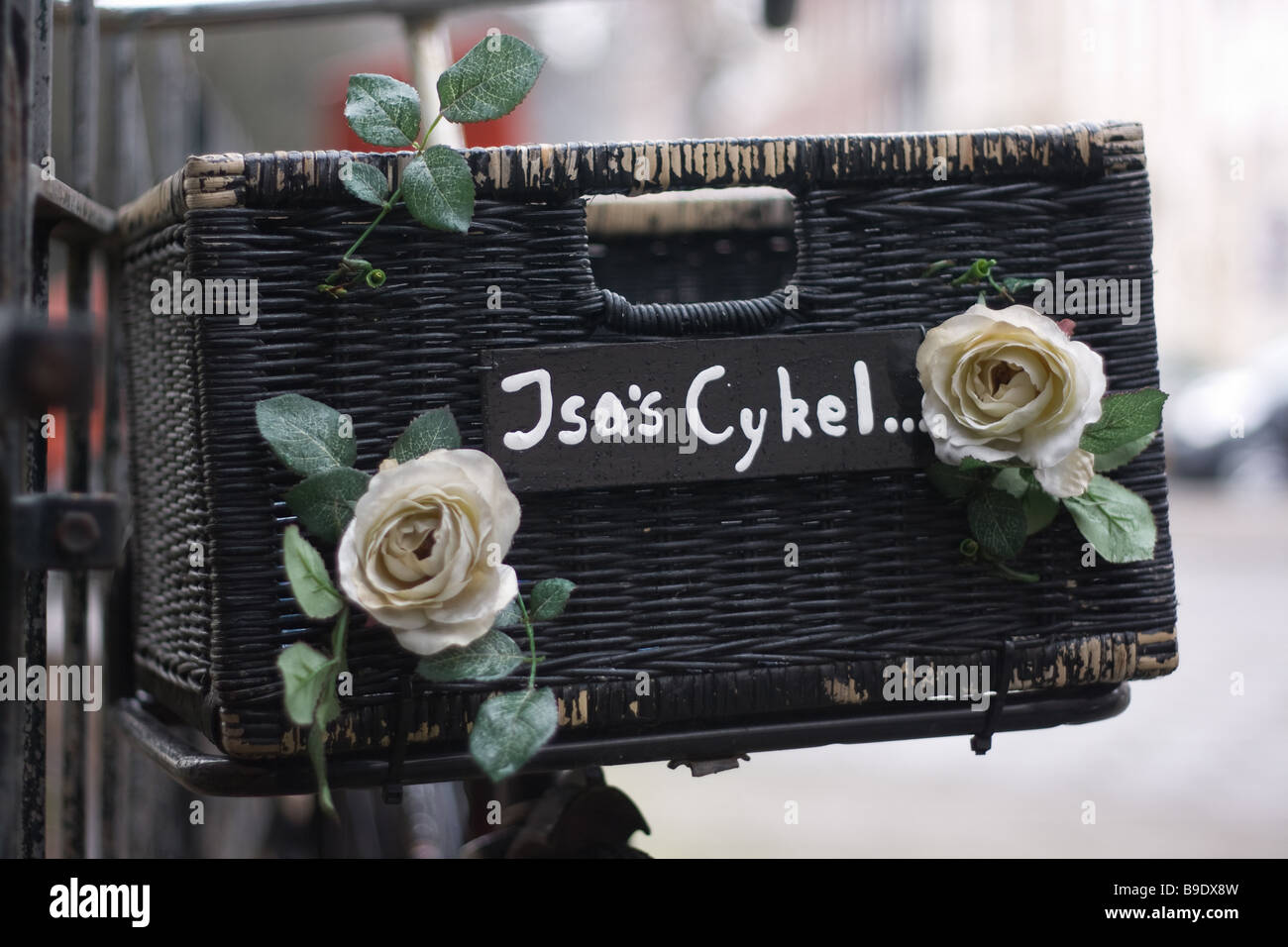 Schwarze Fahrrad Korb mit weißen Blumen (Rosen) und markieren "Jsas Cykel" Stockfoto