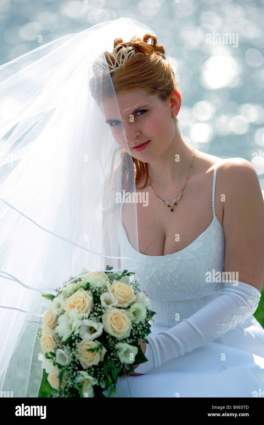 Halben Körper Porträt der lächelnde Braut mit Schleier und Strauß saß vor der See Stockfoto