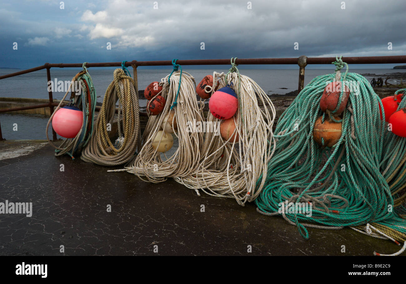 Seile aufgewickelt ordentlich bereit für den nächsten Angelausflug. Sinclair Bay, Caithness, Schottland im Hintergrund Stockfoto