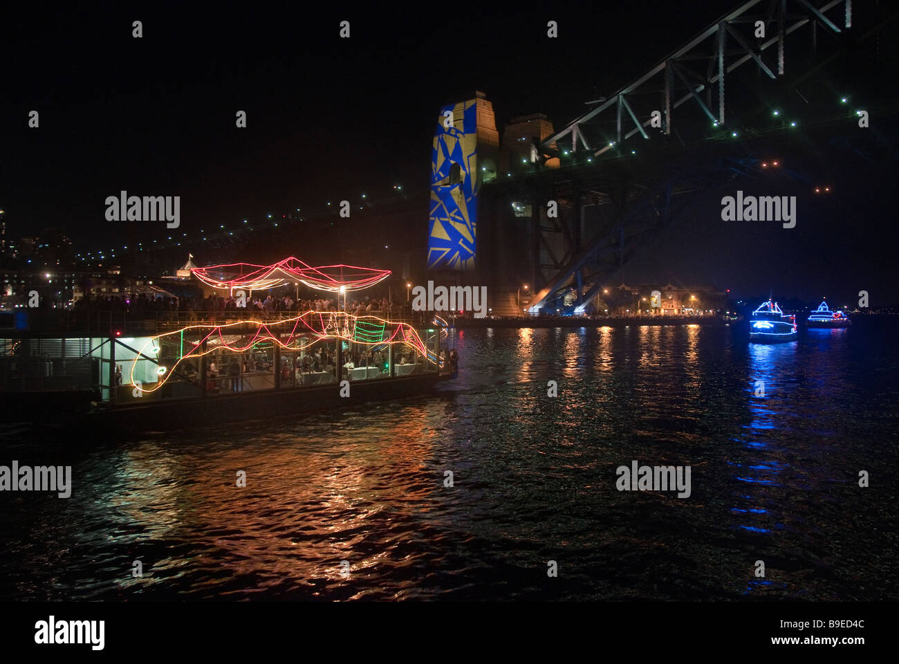 Neujahr-Kreuzer, geschmückt mit bunten Lichtern wie der legendäre Aborigines Regenbogenschlange unterquert den Hafen von Sydney Stockfoto