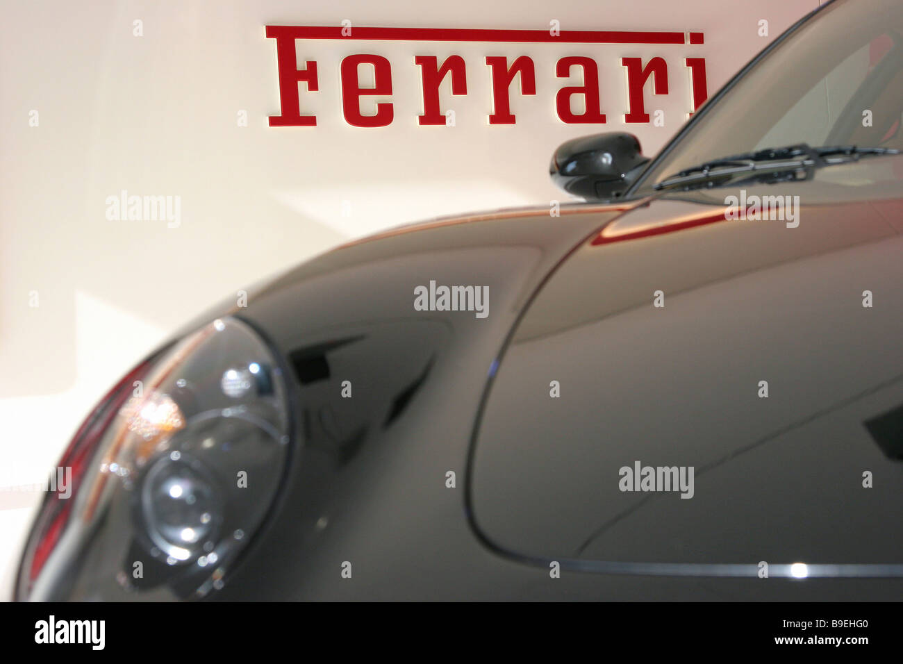 Ferrari-Logo mit einem Ferrari Auto davor Stockfoto