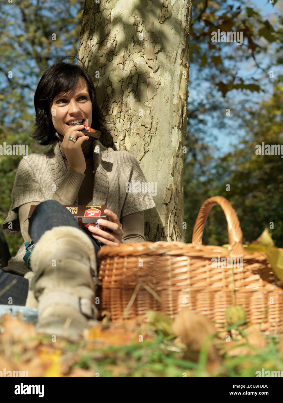 Reife Frau Baum gelehnt und lächelnd Stockfoto
