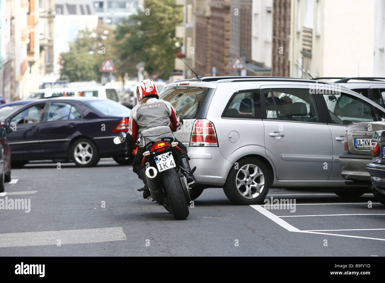 Stadtverkehr Motorradfahrer Rückansicht Auto gefahren-Situation von-Stadt-Verkehr Autos Fahrzeuge Autofahrer Rückwärtsfahren Motorrad parks Stockfoto