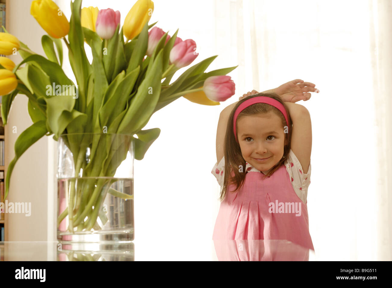 5-8 Jahre Blick Kamera blumeblumenstrauß Blumenvase fröhlich Frühling Frühlingsblumen Frühlingsstrauß Geste Glastisch Stockfoto