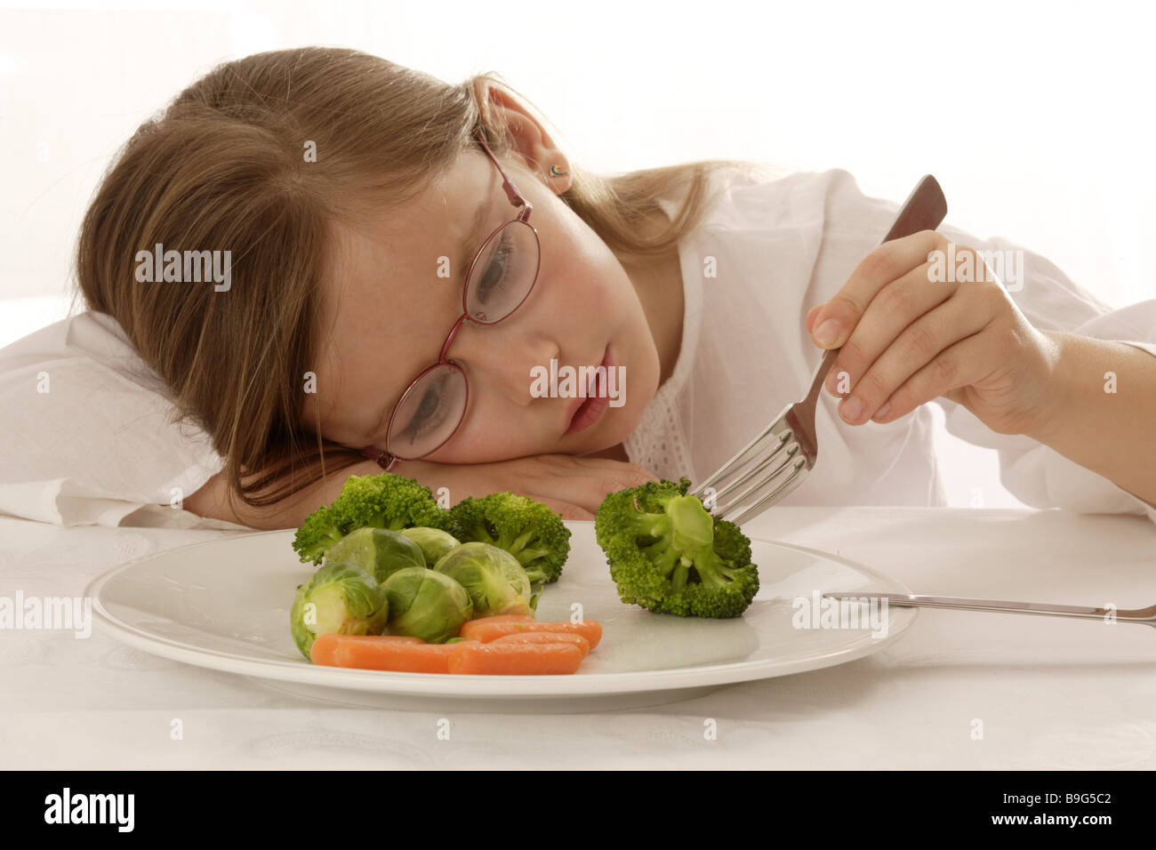 8-10 Jahre Appetit-viele Gläser Brokkoli Brünette Ekel Ernährung essen Gabel versunken in Gedanken Gemüse Ausdruck gesund Stockfoto
