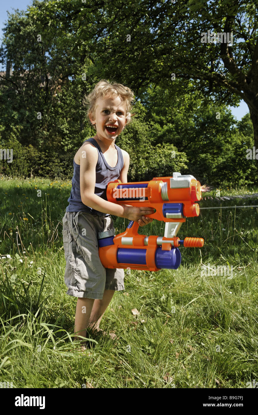 Wiese junge Spritzen Gun spielt Garten Menschen Kind Wasser-Pistole Spielzeug Sommer steht Freude glücklich Spritzer Gesichtsausdruck Schreie Stockfoto