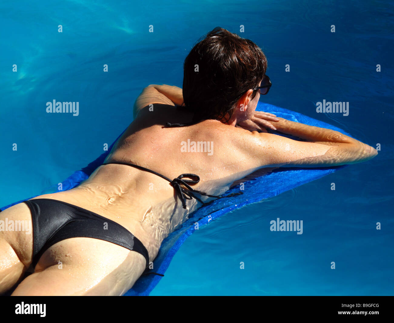 Eine junge Frau liegend auf einer Matte in einem Schwimmbad. Stockfoto