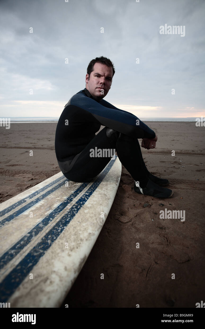 männliche Surfer am Strand sitzen auf langes Brett Stockfoto