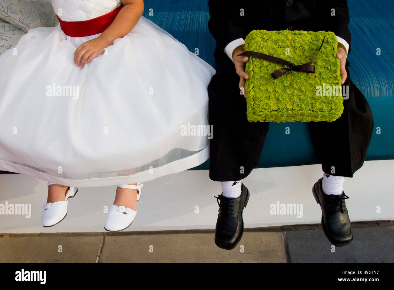 Flowergirl und Ringträger (mit floralen Ringkissen) warten, Füße baumelten, für die Zeremonie zu beginnen Stockfoto