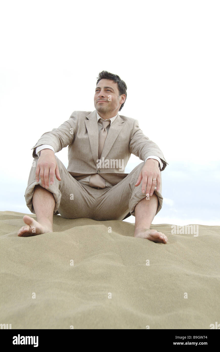Mann Anzug Strand sitzen Entspannung Erholung 30-40 Jahre Anzug ausfallenden Endzeit draußen barfuß Entspannung Erholung Stockfoto