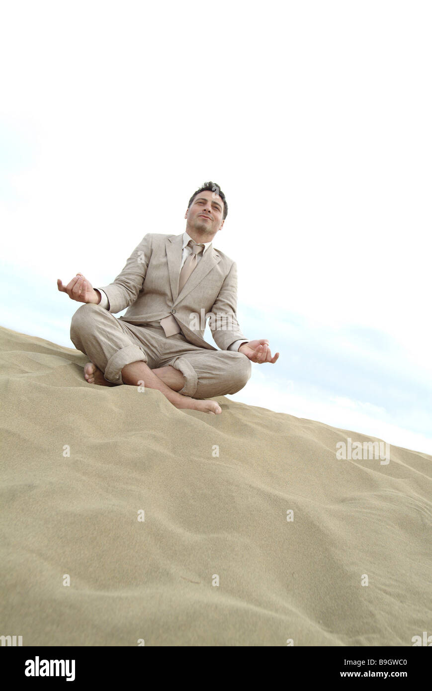 Mann Anzug Strand sitzen Yoga Meditation 30-40 Jahre Anzug ausfallenden Endzeit draußen barfuß Entspannung Erholung Urlaub Stockfoto