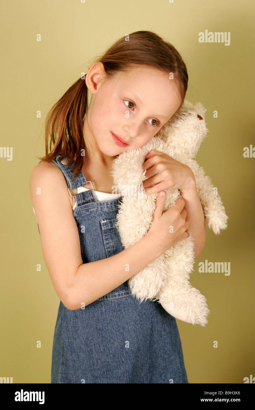 Mädchen Kuscheltier Detail Serie Leute halten Kinder 6-10 Jahre, die blonde Jeans-Kleid Plüsch-Tier kuschelige Tiere tragen schmiegt sich Stockfoto