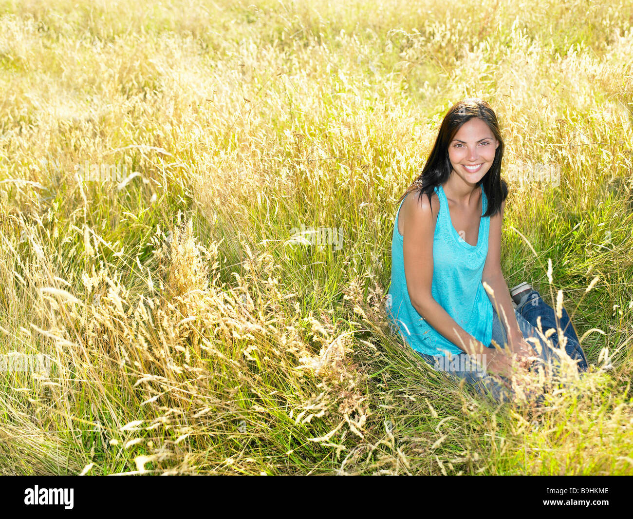 Frau sitzend in einem Feld Stockfoto